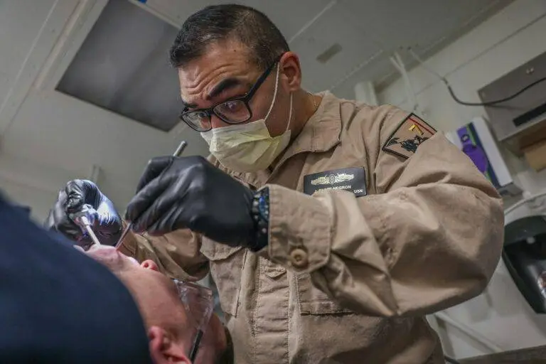 Dentist examining patient's teeth with tools.