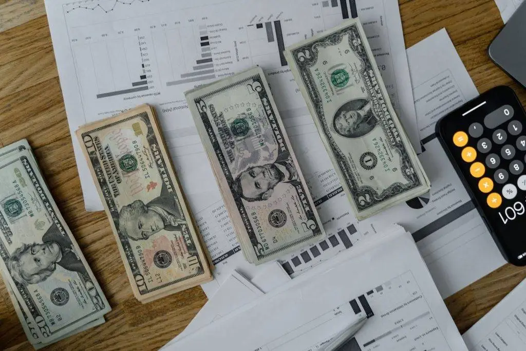 A workspace setup featuring cash, documents, and a calculator symbolizing financial analysis and budgeting.